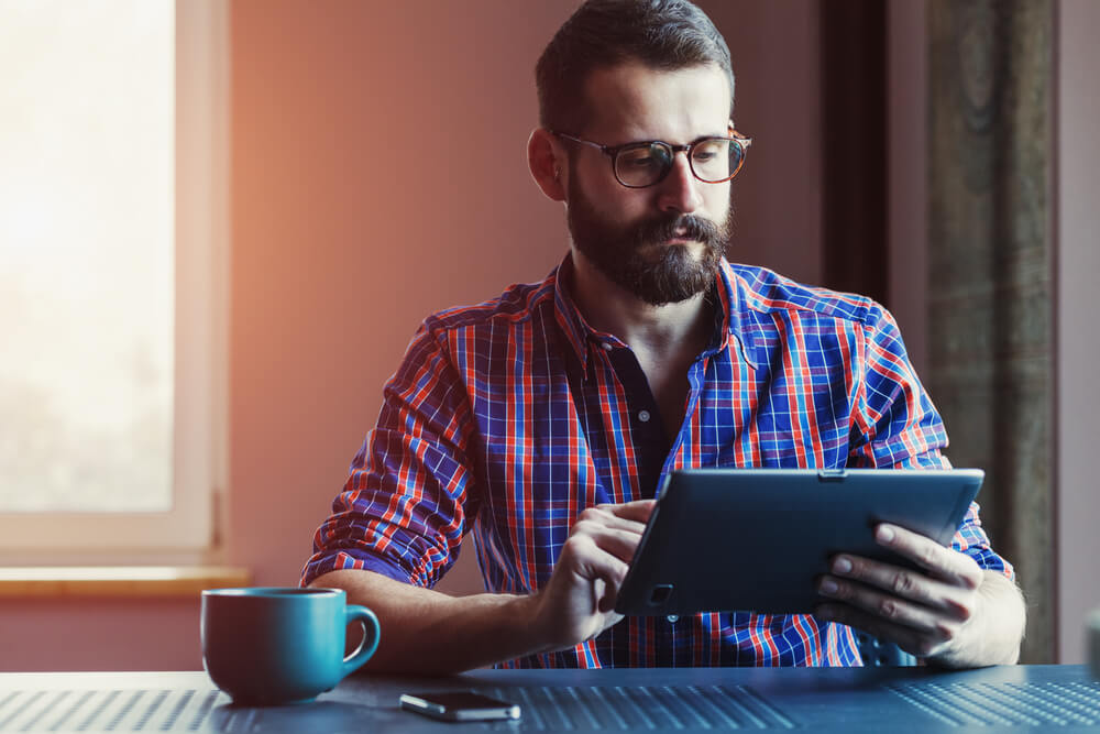 homem acessando tablet sério em café