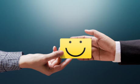 maos masculinas segurando desenho de boneco feliz simbolizando bom relacionamento entre profissional e cliente