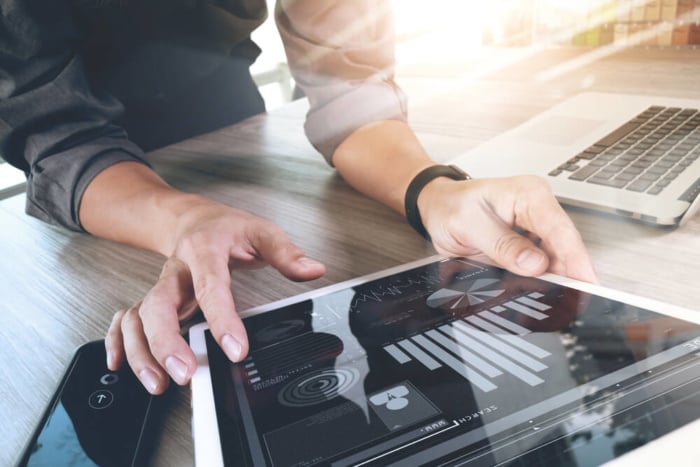 maos masculinas segurando tablet com graficos e estatisticas em tela