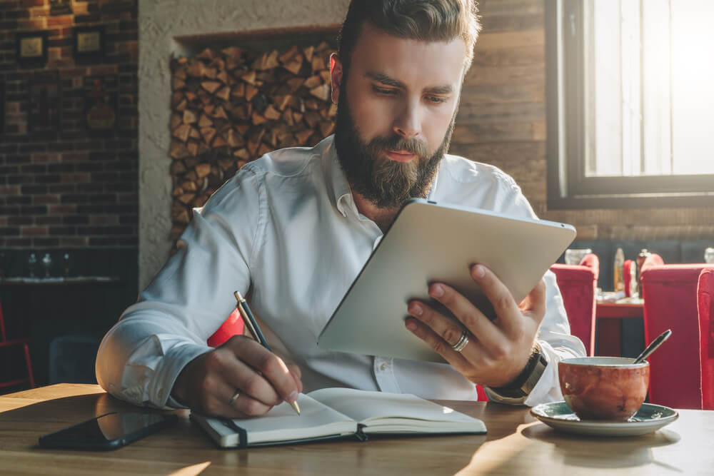 profissional concentrado fazendo anotações e acessando tablet