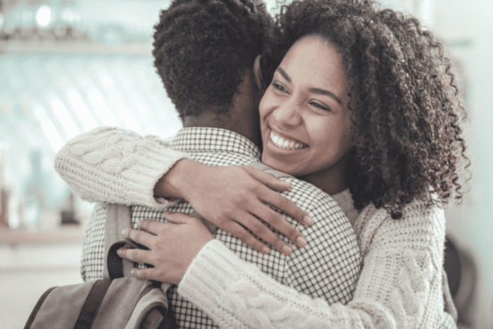 duas pessoas se abraçando sorrindo, representando conexão emocional, pertencimento e necessidades sociais da pirâmide de Maslow.