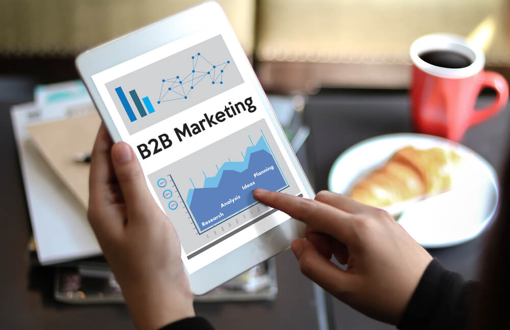 profissional assinalando tablet com tema de B2B Marketing