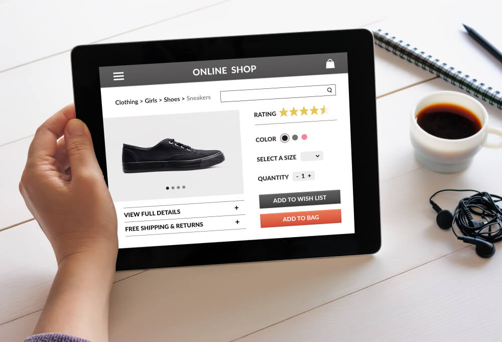 mao feminina segurando tablet com loja online de sapatos em tela