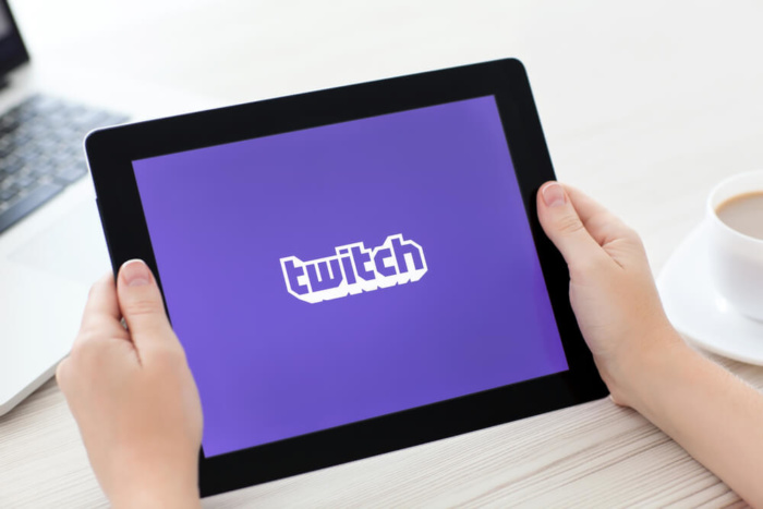 maos femininas segurando tablet com icone de aplicativo twitch em tela