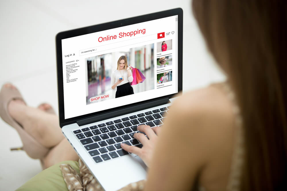 mulher usando laptop em pagina de e-commerce de roupas e acessorios