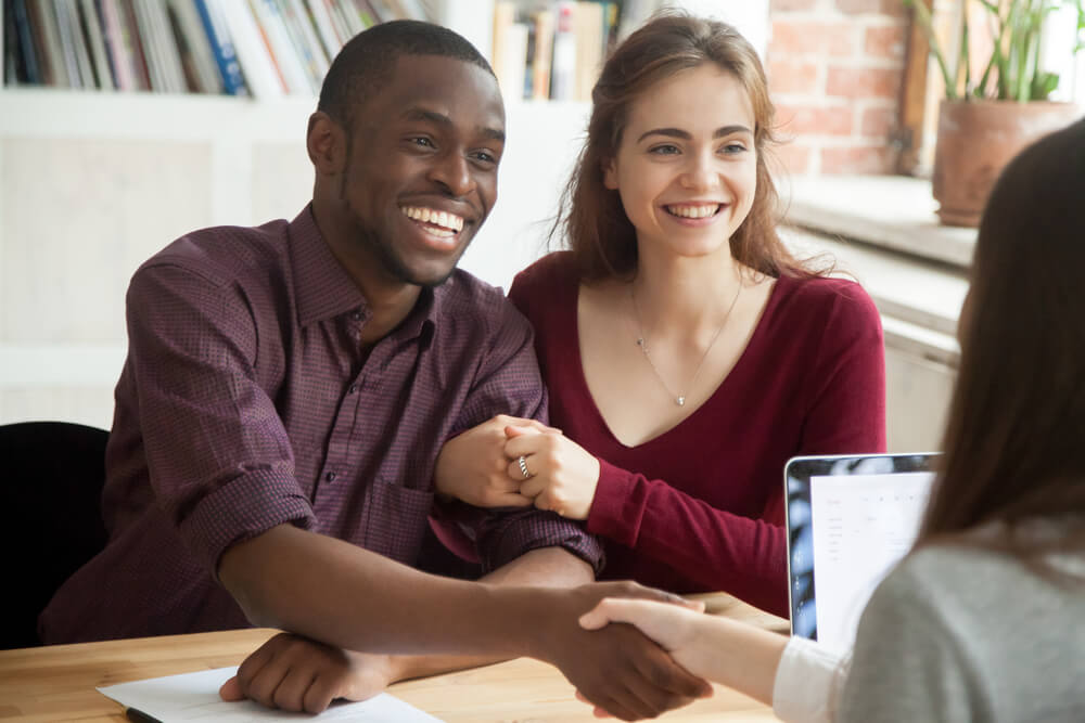 profissional apertando mao de clientes com expressao sorridente em escritorio