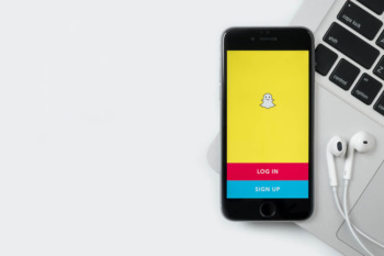smartphone sob teclado de laptop com pagina de aplicativo snapchat em tela