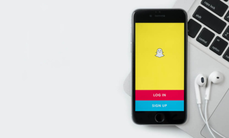 smartphone sob teclado de laptop com pagina de aplicativo snapchat em tela