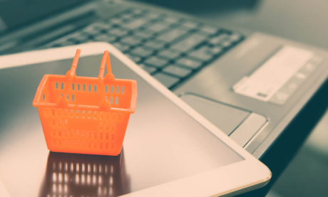 tablet em teclado de laptop com mini cesta de compras sob o mesmo