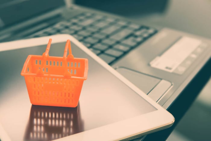 tablet em teclado de laptop com mini cesta de compras sob o mesmo