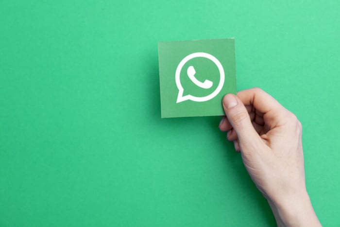 mao segurando folha com icone do aplicativo whatsapp com fundo verde
