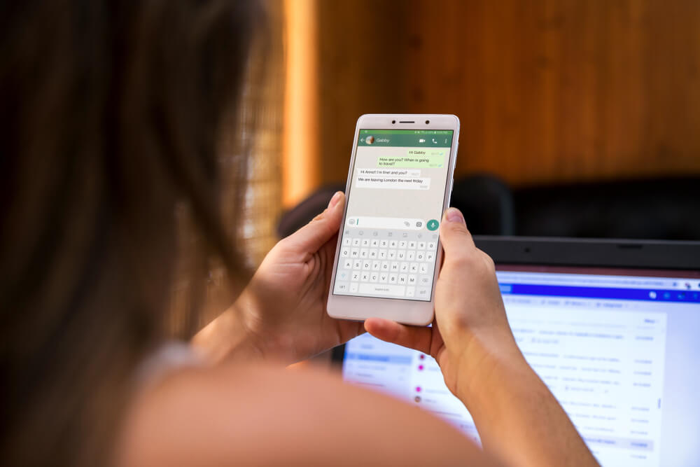 mulher segurando smartphone com conversa no whatsapp em tela