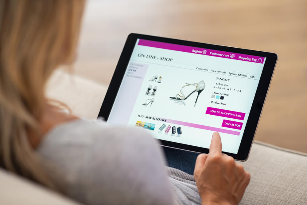 mulher segurando tablet em pagina de ecommerce visualizando produto