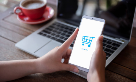 maos femininas segurando smartphone com carrinho de compras em tela simbolizando o e-commerce