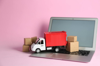 mini caminhão e caixas em cima de laptop em fundo rosa simbolizando o e-commerce