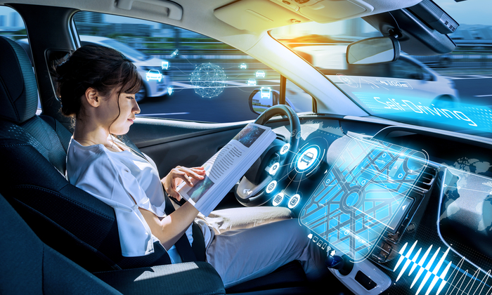 A person reading a book while using a self-driving car.