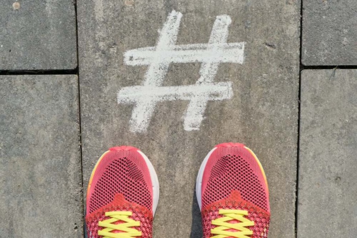 hashtag pintada no chão junto de tênis de corridoa para contas no instagram sobre saúde e fitness