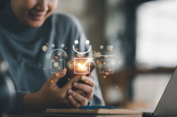Customer service evaluation concept. smiling Asian female Is using a smartphone And she is pressing face emoticon smiling in satisfaction on virtual touch screen.