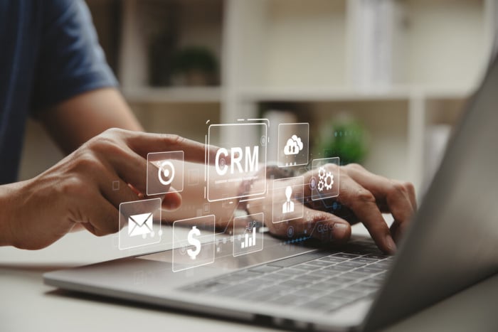 gráficos representando um CRM flutuando sobre um teclado de notebook