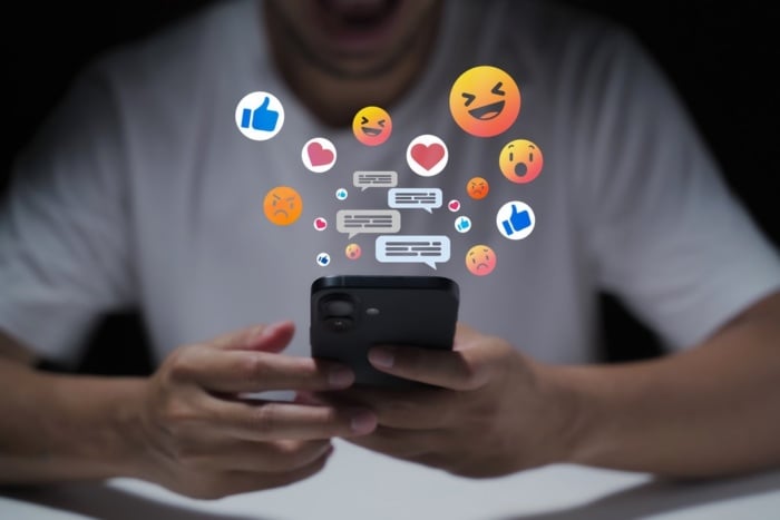 Pessoa acessando redes sociais com ícones de emojis surgindo na tela
