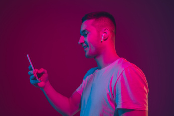 Caucasian man’s portrait isolated on pink studio background in neon light