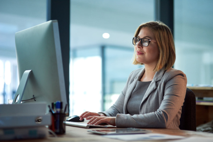Donna professionista lavora al computer in ufficio, concentrata sull’analisi e sulla gestione di progetti digitali.