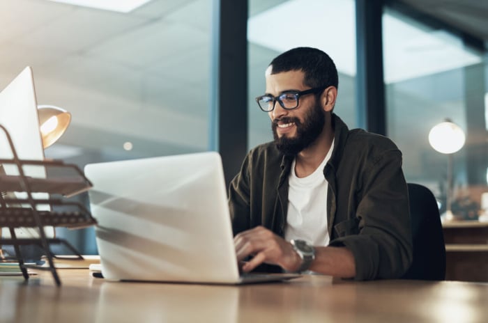 Homme travaillant sur un ordinateur portable dans un bureau moderne, concentré sur une stratégie de contenu.