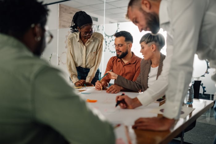 Grupo de profissionais de marketing analisando relatórios e gráficos de desempenho sobre a mesa, em um exemplo prático de como fazer um briefing para diferentes tipos de projetos de marketing