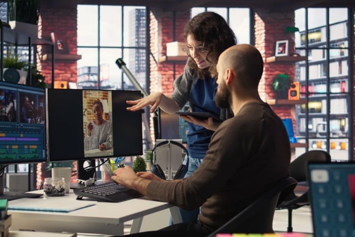 Profissionais trabalhando em computadores dentro de uma moderna agência de IA com estilo de escritório industrial.