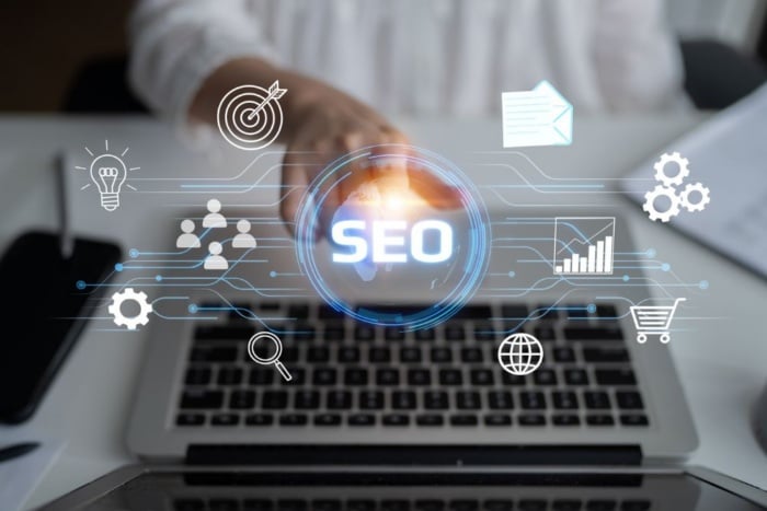 Consultoria de SEO global: interface digital holográfica com o termo SEO centralizado sobre o teclado de um notebook, destacando ícones de dados, engrenagens e alcance global.