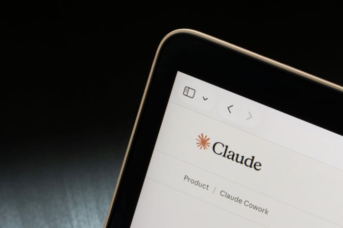 Foto aproximada da tela de um dispositivo exibindo a interface do Claude, com o logotipo no centro e menu de navegação com indicação de produto e Claude Cowork.
