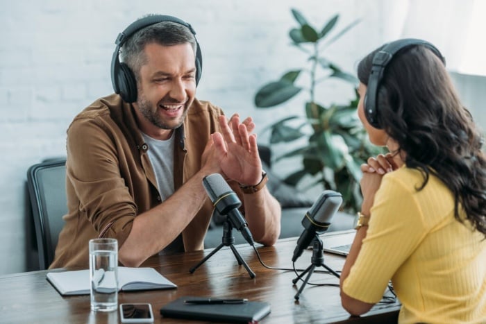 homem e mulher conversando em uma mesa para um podcast